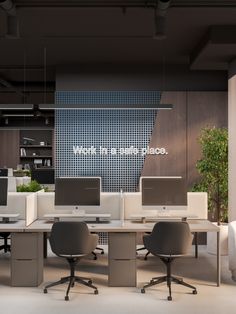 an office cubicle with multiple computers and chairs