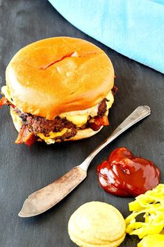 a cheeseburger and some macaroni and cheese on a slate board with a knife