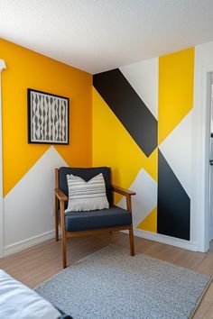 a chair in front of a yellow and black wall with geometric designs on it's walls