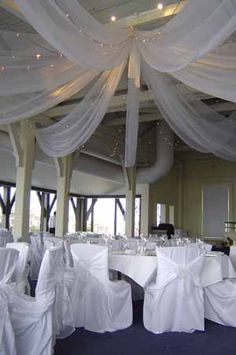 the banquet room is set up with white linens and draping on the ceiling