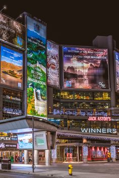 a large building with lots of billboards on it's sides at night time