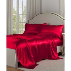 a bed covered in red sheets and pillows