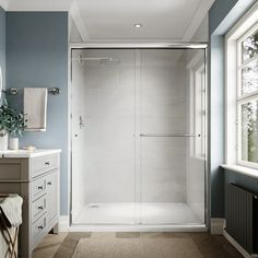 a bathroom with a walk in shower next to a white sink and mirror on the wall