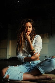 a woman sitting on the floor with her hand under her chin