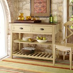 a dining room table with two chairs and a bowl of fruit on it's shelf