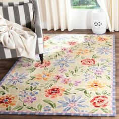 an area rug with flowers on it in front of a chair and window sill