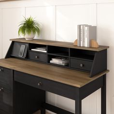 a black desk with drawers and a potted plant