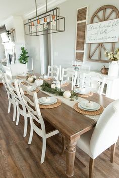 a dining room table set with white chairs and place settings for the centerpieces