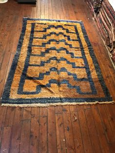 an old rug is laying on the floor in a room with wooden floors and walls