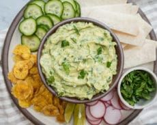 a plate with chips, cucumber and guacamole