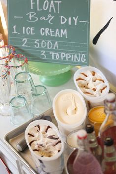 an assortment of ice creams and toppings on a tray with a sign in the background