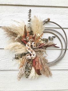 a wreath made out of dried plants and feathers