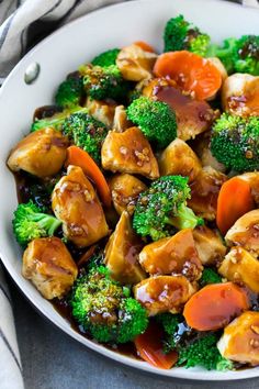 a white bowl filled with chicken and broccoli on top of a gray table