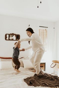 a woman standing on top of a bed next to a child