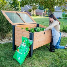 a woman sitting on the ground next to a garden box