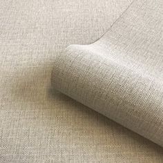 a close up view of the fabric on a beige couch with a white wall in the background