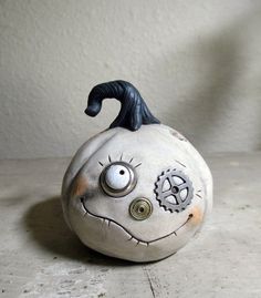 a white pumpkin with a black nose and eyeballs on it's side sitting on a table