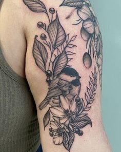 a woman's arm with a bird and leaves tattoo on it