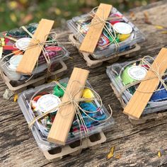 four small boxes filled with different types of crafting supplies on a wooden table outdoors