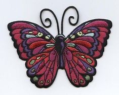 a red and purple butterfly sitting on top of a white surface with an iron frame