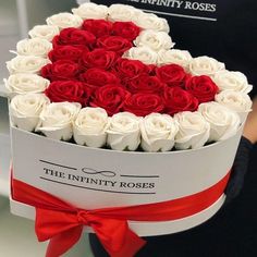 a heart shaped box filled with white and red roses