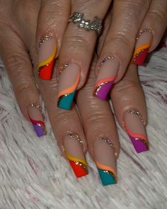 a woman's nails with multicolored nail polish and gold accents on them