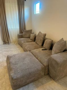 a large sectional couch sitting in the middle of a living room next to a window