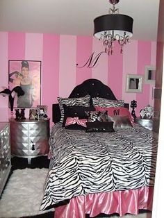 a bedroom decorated in pink and black with zebra print on the bed, dressers, and chandelier