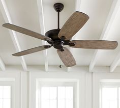 a ceiling fan in a room with white walls and wood trimmings on the ceiling