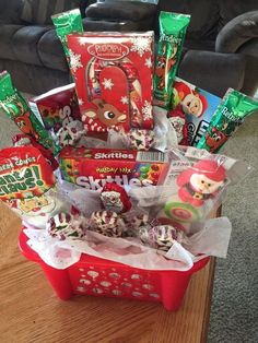 a red basket filled with candy and candies on top of a wooden table next to a couch