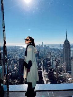 a woman standing on top of a tall building looking out at the city below her