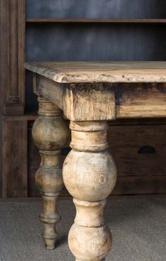 an old wooden table sitting in front of a book shelf