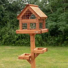 a wooden bird house with two windows and a roof made out of wood, sitting in the grass