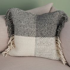 a gray and white pillow sitting on top of a couch