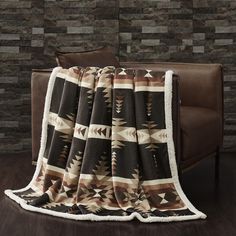 a couch with a blanket on top of it in front of a brick wall and wooden floor