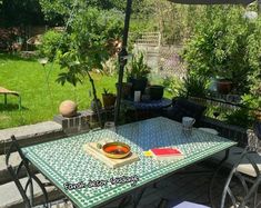 an outdoor table and chairs in a backyard area with green grass, trees and bushes