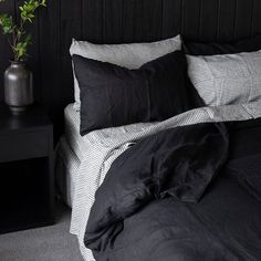 a black and white striped bed with two vases on the nightstand next to it