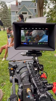 a video camera set up in front of a group of people sitting on the grass