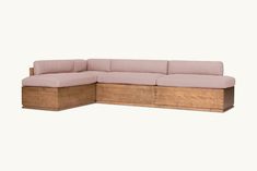 a wooden sectional couch sitting on top of a white floor next to a pink wall