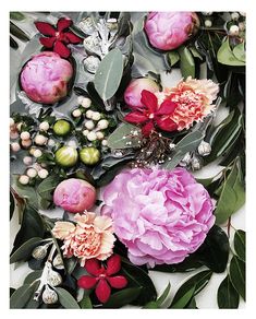 an arrangement of flowers and leaves on a white surface