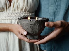 two people holding a small candle in their hands