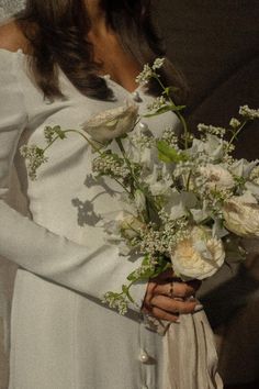 a woman in white dress holding a bouquet of flowers