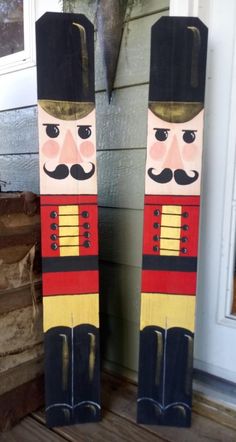 two wooden nutcrackers sitting on top of a porch next to a door