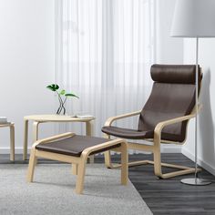 a black chair and ottoman in a room with white walls, flooring and curtains