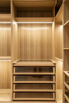 an empty walk in closet with wooden shelves and lights on the ceiling, along with other open shelving units