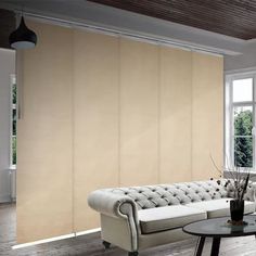 a living room filled with furniture and windows covered in shades of light beige fabric covering the walls