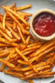 french fries and ketchup on a plate next to a bowl of ketchup