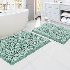 two bath mats sitting on top of a white floor next to a tub in a bathroom