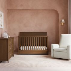 a baby's room with a chair, crib and dresser in it is shown