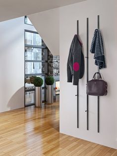 there is a coat rack with two coats hanging on it and a purse next to it